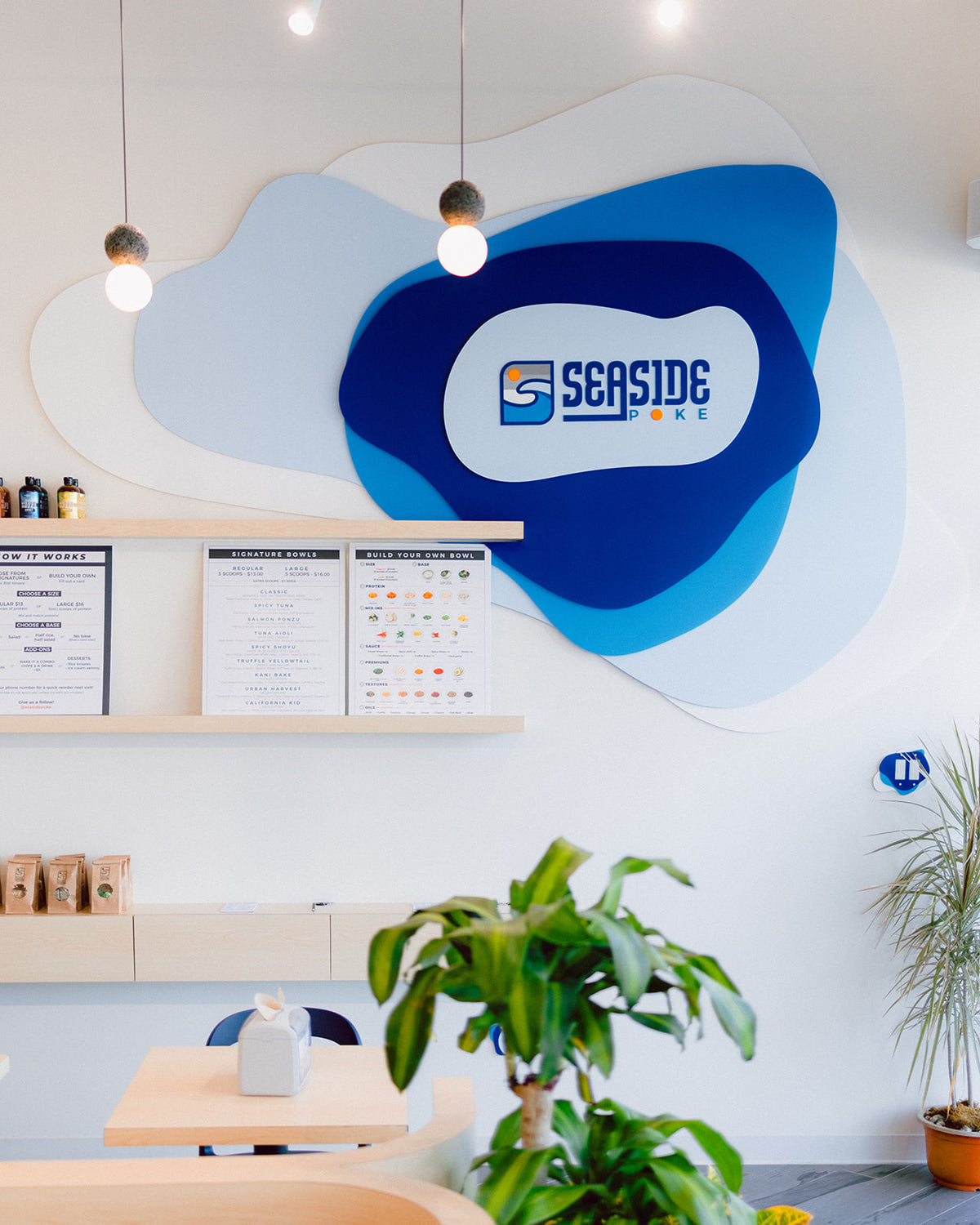 AALVO custom brand signage. Laser cut sign for Seaside Poke restaurant on wall. Various blue colors overlayed for the decorative sign.