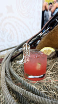 AALVO custom event detail. A red cocktail with a lemon slice on the side, garnished with a cowboy drink charm.