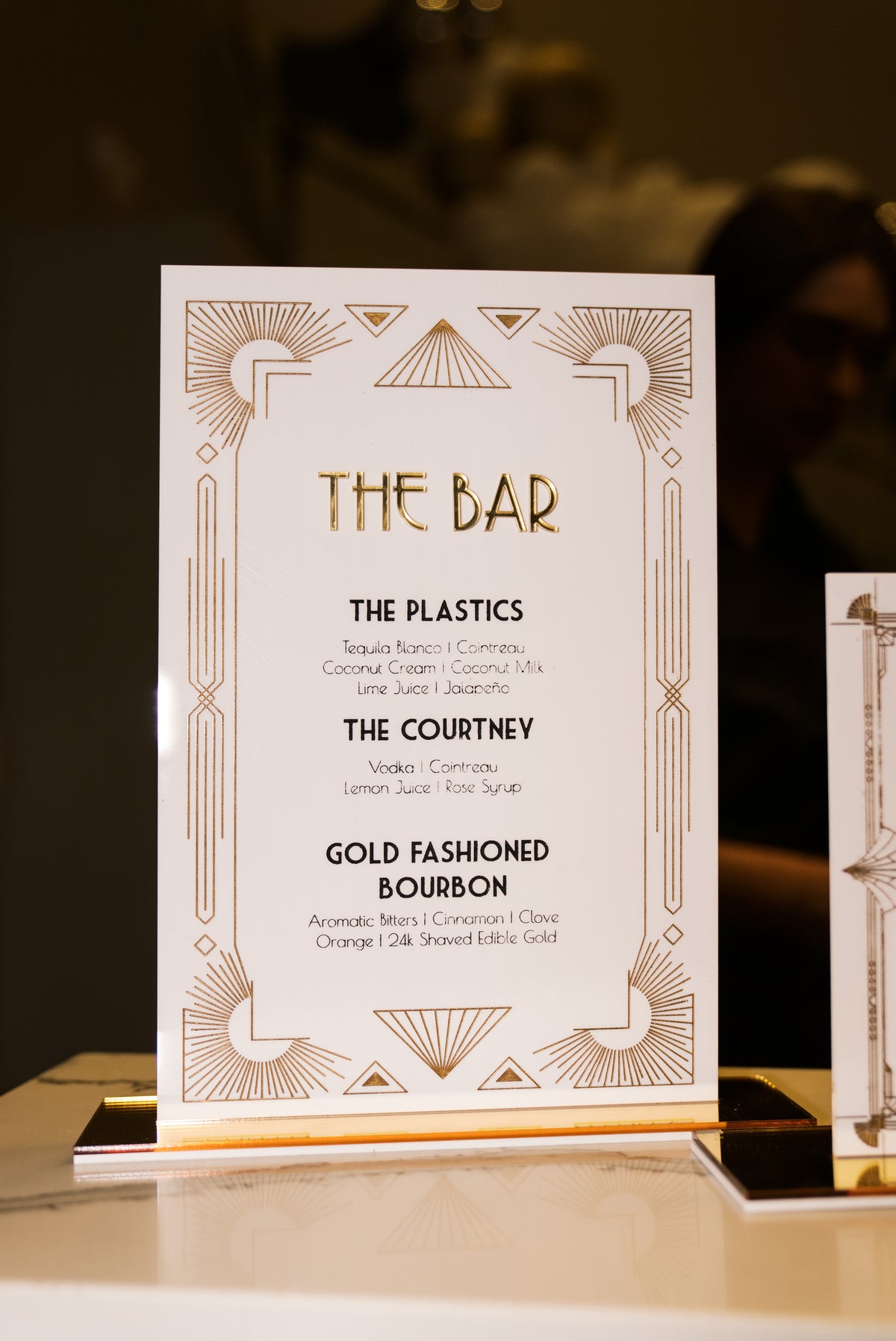 AALVO custom event signage for a luxury event. Gold art deco acrylic bar menu sign listing signature cocktails at a event reception.