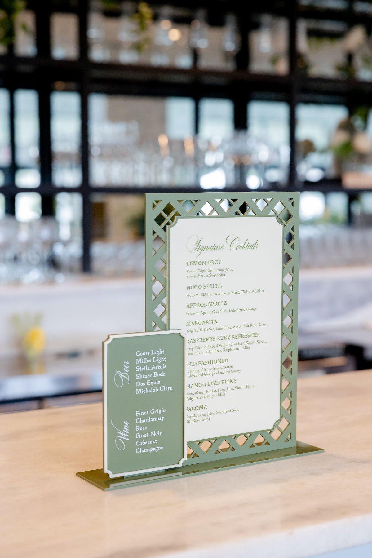 AALVO custom wedding signage. Sage green laser-cut lattice bar menu sign with cocktail list and matching beer and wine sign