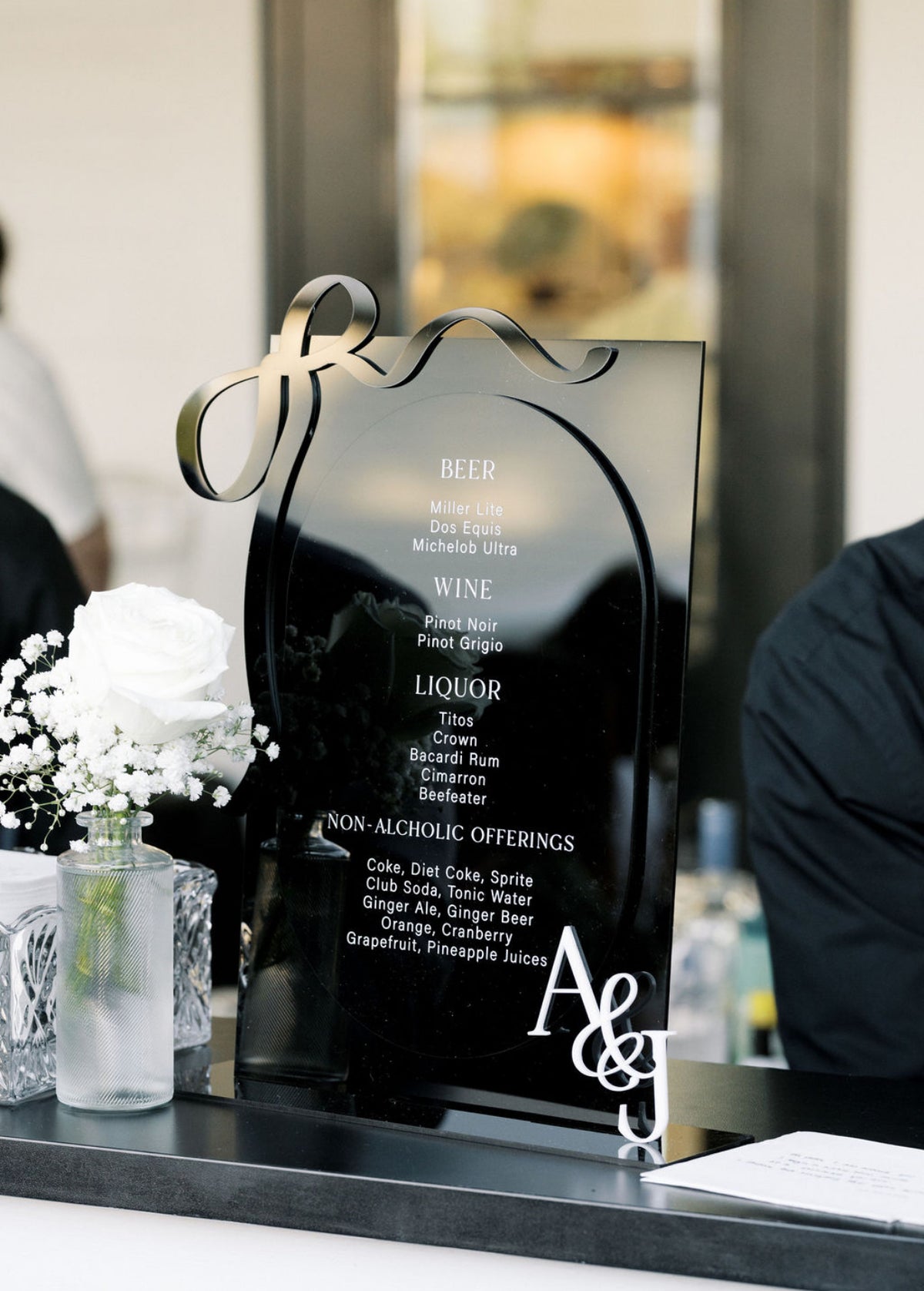 AALVO custom wedding signage. Decorative bar menu in black with laser cut bow in black and laser cut 'A&J' in white attached to it.