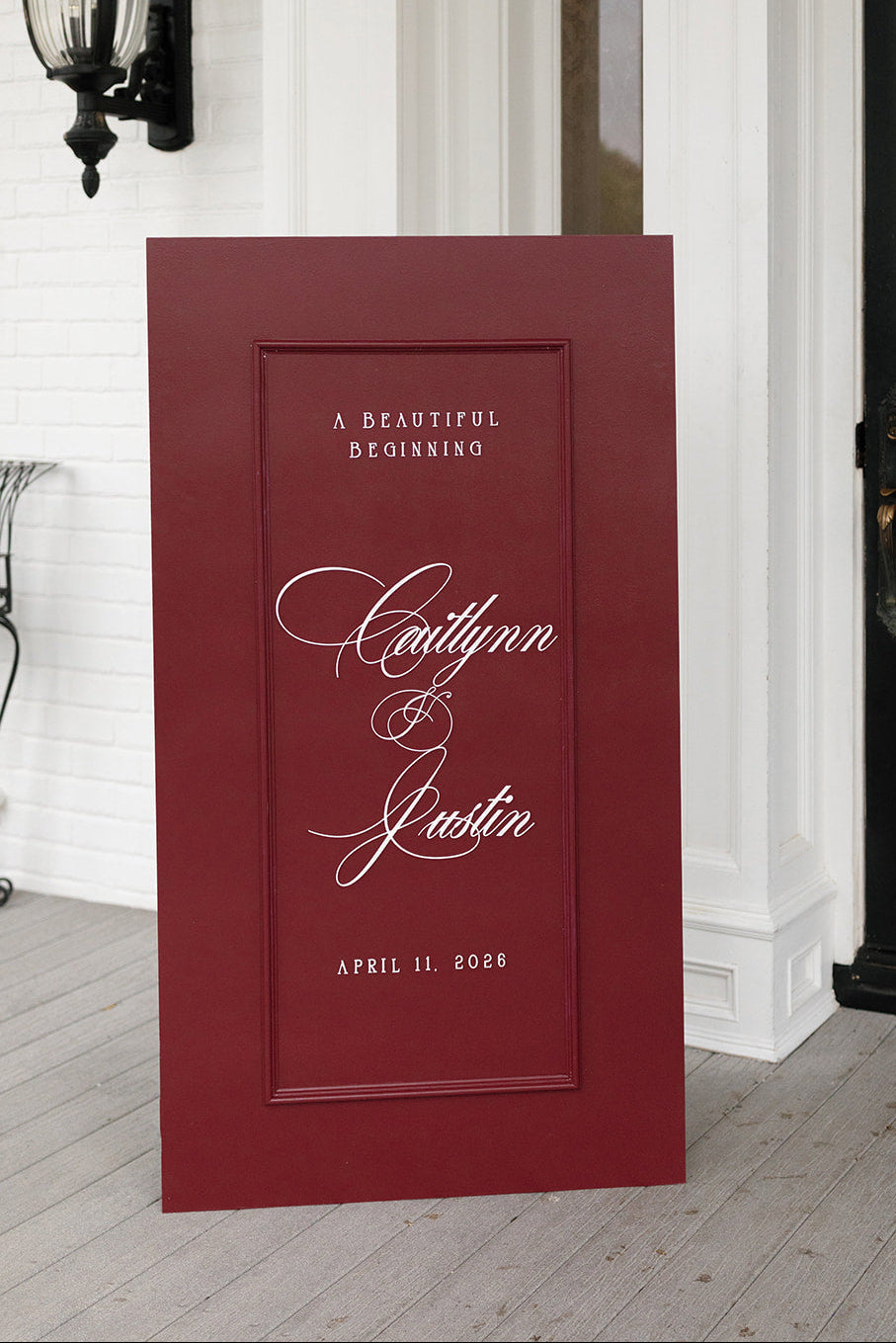 AALVO custom wedding signage. A tall, rectangular red wedding sign with white script text reading 'A Beautiful Beginning' and the names of the bride and groom.
