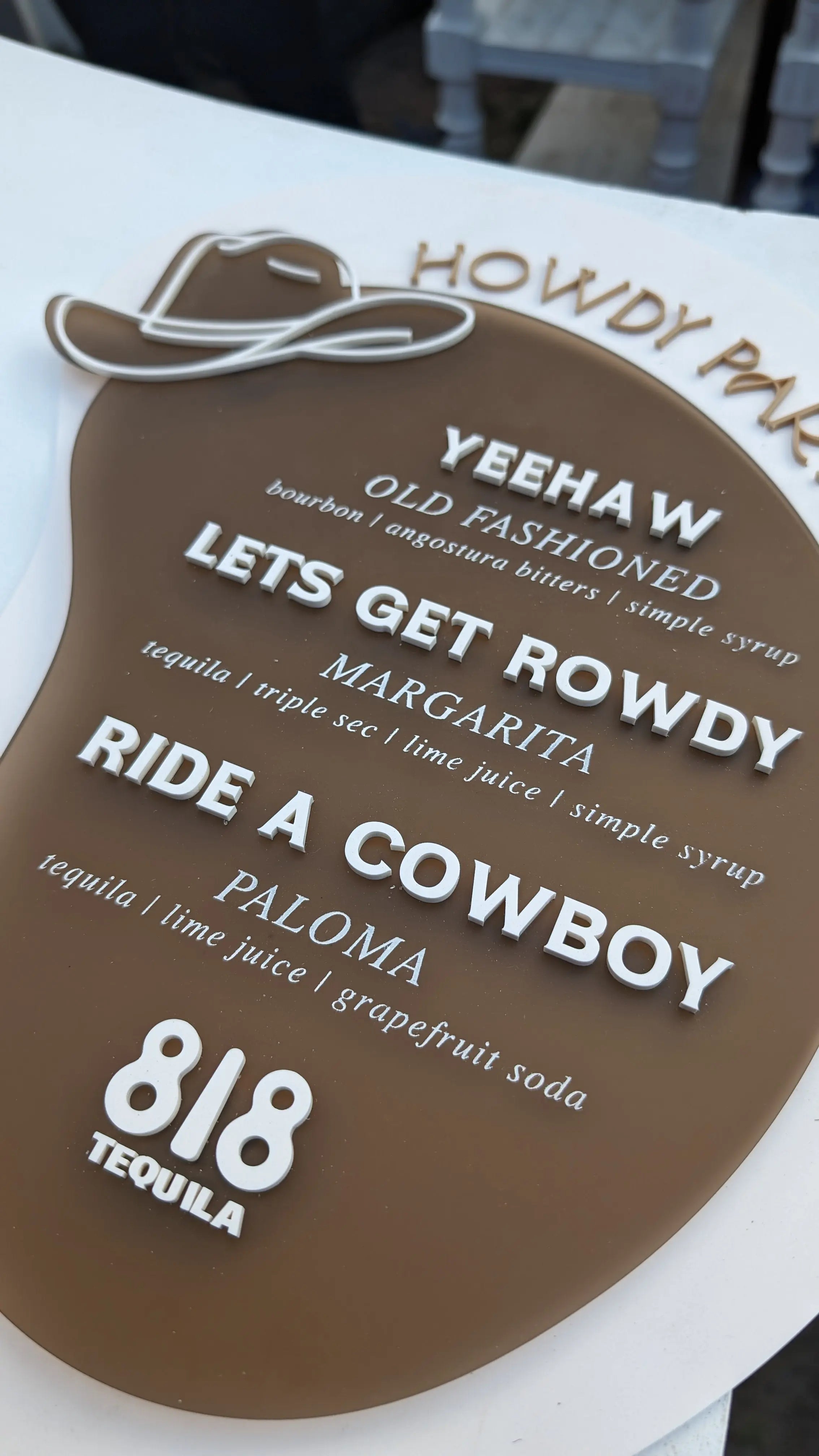 Brown acrylic with beige and white text. Cowboy hat accent and western font